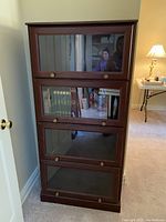 Front view of the full bookcase showing all four glass-front compartments and brass-tone knobs.