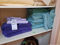 Shelves with stacked purple, blue, teal, and beige folded towels including bath and hand towel sizes.