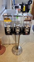 Frontal view of triple candy dispenser on chrome stand with two M&M’s hoppers and one generic hopper