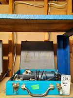 Bosch electric jigsaw in open blue metal case showing entire tool and cord wrapped inside.