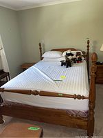 Full view of the four post wood bed frame with mattress and pillows showing overall structure and size.