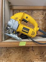 Side view of the DeWalt DW317 orbital jigsaw on a wooden shelf with metal base plate and ergonomic yellow handle.