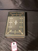 Front cover showing dark green leather with gold gilt detailing and decorative border.