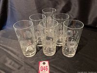 Photo showing all six Hughes etched cornflower drinking glasses together on a black cloth background.
