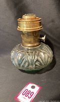 Side view of vintage Aladdin lamp base showing textured glass body with brass burner top.