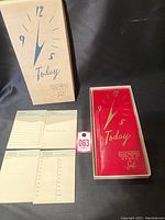 Photo showing closed original box with Art Deco clock design and partially visible memo pads