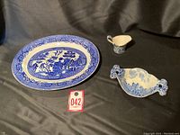 Full set showing the oval serving dish, candy dish with handles, and small pitcher on a black background.