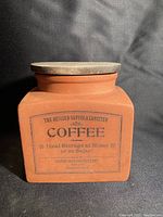 Front view of square terracotta coffee canister with printed label and wooden lid