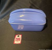 Closed blue refrigerator dish with ridged lid and gold trim on black background