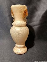 Full front view of the textured opaque white vintage Murano glass bud vase with curled amber glass handles, on black background.