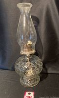 Full view of vintage glass oil lamp with bee hive pattern, clear glass and pie crust top chimney.
