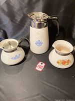 Lot contents showing blue and white tea pot, creamer/sugar bowl, and orange and gold tea pot (no lid) on black background