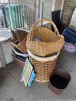Photo showing stacked wicker baskets in various sizes and weaving styles with a framed picture leaning against a tall basket.