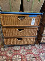 Front view of wicker 3-drawer chest with metal frame showing drawer fronts and storage baskets on top.