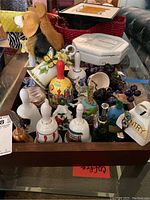 Wooden tray filled with assorted souvenir bells, trinket boxes, and faux floral picks showing variety of items and condition.