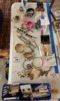 Full overview of the costume jewelry lot showing a variety of bracelets, rings, brooches, watches, and pendants spread on a surface.
