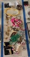 Overview photo of costume jewelry laid out on a flat surface featuring bead necklaces, bracelets, earrings, and a brooch