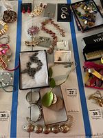 Various costume jewelry pieces laid out including earrings, bracelets, necklaces, and a keychain, some in packaging or display boxes.