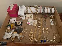 Full view of assorted costume jewelry including bracelets, necklaces, earrings, and pins arranged in a box