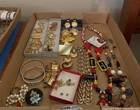 Full display of assorted costume jewelry including bracelets, earrings, chain necklaces, and colorful bead necklaces with charm pendants.