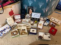Full view of the assorted costume jewelry in various boxes on carpeted floor showing range of styles and colors.