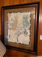 Framed Texas 1836 map hanging on a wood-paneled wall, showing detailed map and frame.