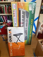 Photo of boxed Casio LK-56 keyboard and Quik Lok BX-9 adjustable keyboard bench.