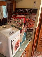 Breadman TR442SPR breadmaker with chief basket inside, stove top grill in original box, Oneida pizza stone with rack, and Rival crockpot.
