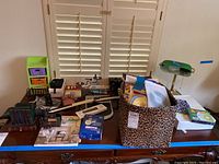 Wide view of desk with green glass desk lamp, leopard print storage box, books, and various office supplies spread out.