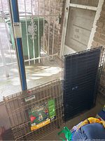 Photo of two pet enclosures including a gold-tone Precision exercise pen and a black Top Paw folding crate.