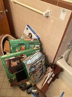 Full view of the lot showing various pet supplies including boxed kennel, bed, steps, and pet tray stacked in a bathroom corner.