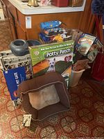 Lot items including Potty Patch box, brown pet bed in front, pet gates, basket of toys, and pet water/food bowls arranged together