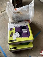 Two cube grid organizers in original boxes, stacked together in a white plastic bag on the floor.