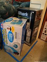 Boxes of Shark Navigator Light vacuum and Hurricane 360 Spin Mop showing branding and product images.