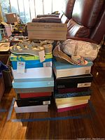 Stack of shoe boxes with various women's shoes on top including sandals and flats