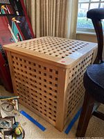 Large IKEA wooden crate showing lattice design and square dimensions, placed on carpet near a chair and window.