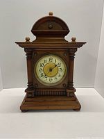 Front view of the antique wooden mantel clock showing full clock structure and wooden finishing.