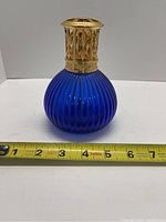 Full view of blue glass body measuring about 4 inches tall with tape measure for scale
