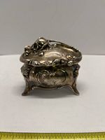 Front view of a silver plated Victorian Art Nouveau jewelry casket with ornate floral and scroll designs, shows tarnish and wear consistent with age.