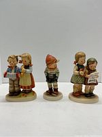 Front view of three Hummel figurines showing detailed hand painting and facial expressions.