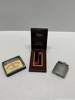 Photo of three vintage lighters: Fisher electronic lighter in case, British Textiles Company advertising lighter with box, and small metal lighter.