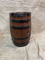 Full view of the vintage oak barrel showing its wooden staves and metal bands with a small hole on the side.