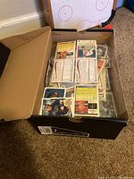 Opened shoebox filled with loose and sleeved baseball trading cards stacked inside