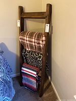 Front view of the wooden blanket rack with blankets draped over it, showing overall height and design.