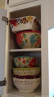 Set of 6 decorative bowls stacked in kitchen cabinet with visible floral and polka dot patterns
