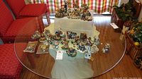 View of large assortment of Boyds Bears figurines arranged on a glass table with a white cloth beneath some pieces, total about 33 figurines.