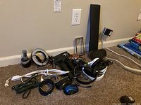 Light ring, headphones, cords, power strips, and TV mount laid on carpet floor showing full lot contents