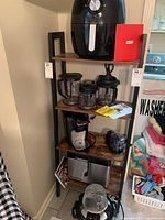 Full view of kitchen appliances on wooden shelving including Dash air fryer, coffee maker with carafe, blender components, bread maker and toaster oven.
