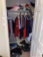 Closet view showing men’s shirts, jackets, and shoes on floor.