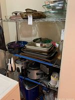 Full view of metal wire shelf loaded with various kitchen cookware and appliances, showing layered contents on multiple shelves.